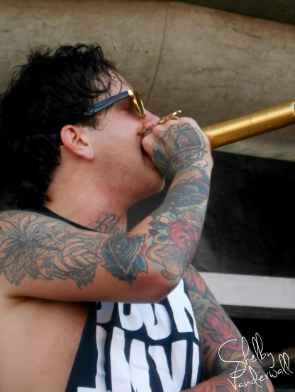 a guy with tattoos holding a pair of gold binoculars