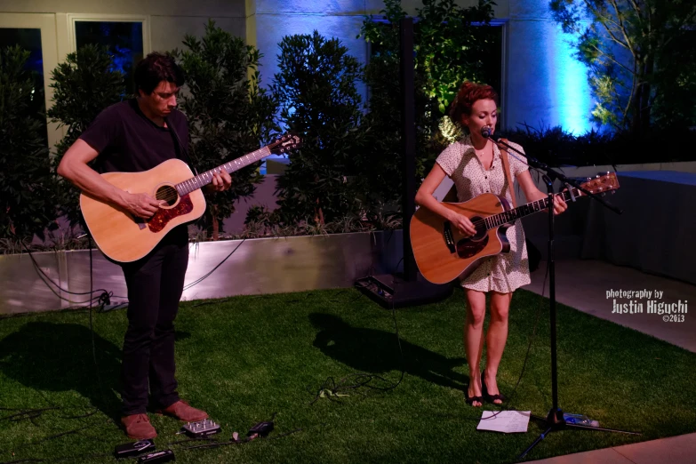 a man and woman sing while playing guitars