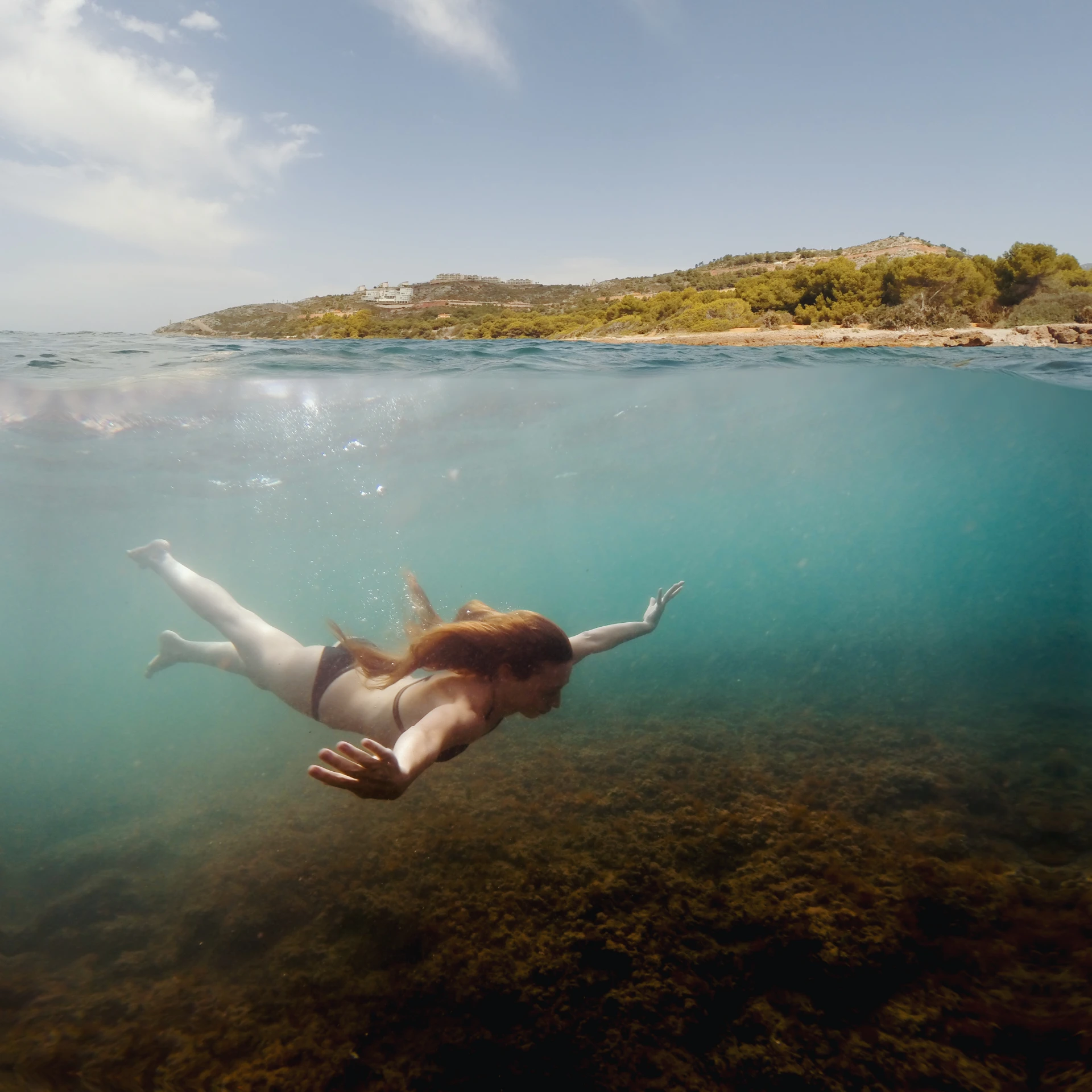 woman swimming in the sea with a long body, revealing skin and legs