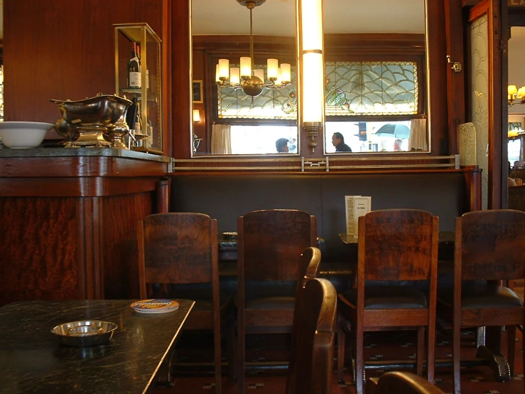 a dimly lit restaurant with wood chairs and stained glass windows