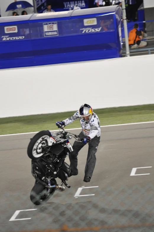 a motorcycle stunt with a person on the back wheel leaning on the bike