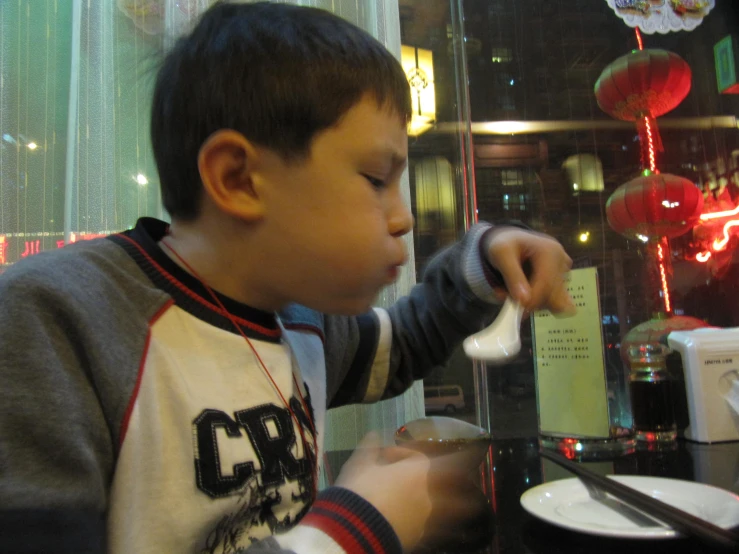 there is a small boy at a table eating some food