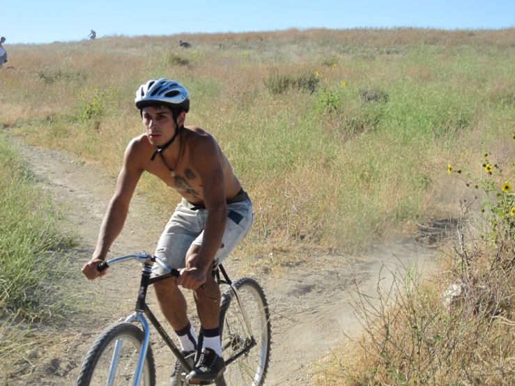 a shirtless man riding a bicycle on a trail