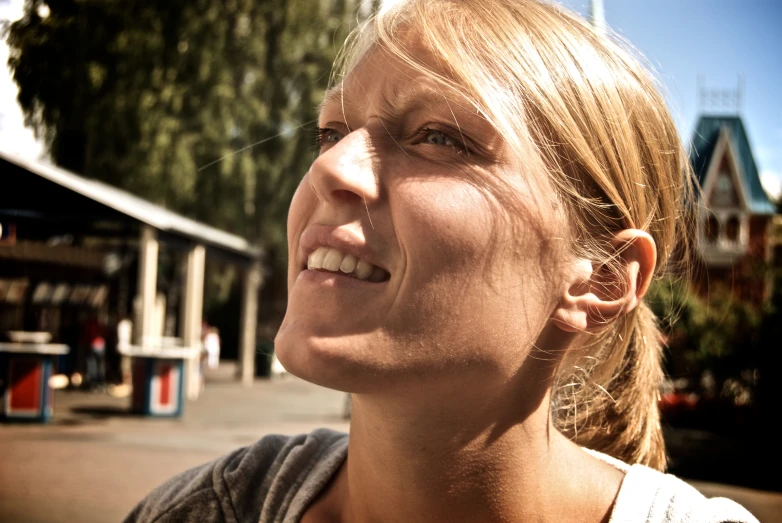 a smiling blonde woman stands in a town street