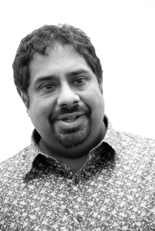 a smiling man in a flowered shirt posing for the camera