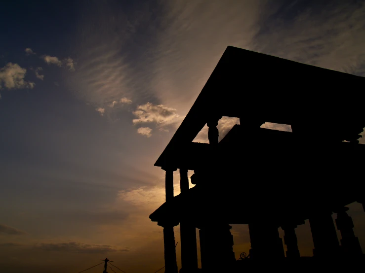 a building is silhouetted against a cloudy sky