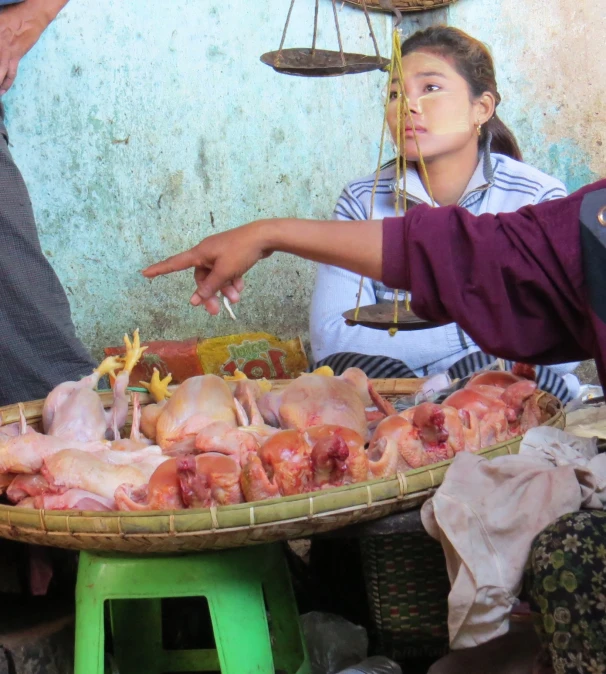 a woman is putting some kind of meat on top of other chicken