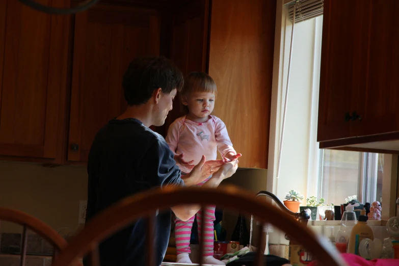 a young man holding onto a little girl looking out the window