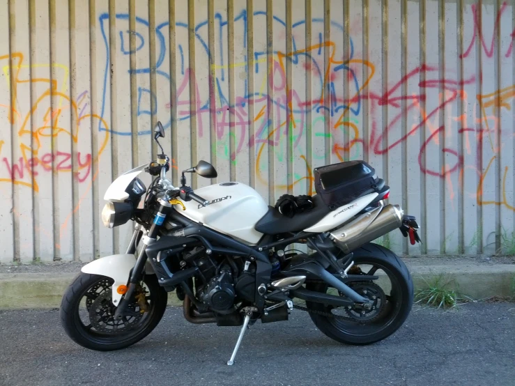 a white motorcycle parked next to graffiti on the wall
