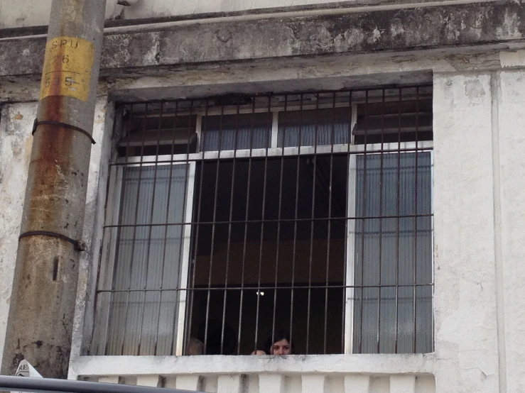 a person is standing in an open window with bars