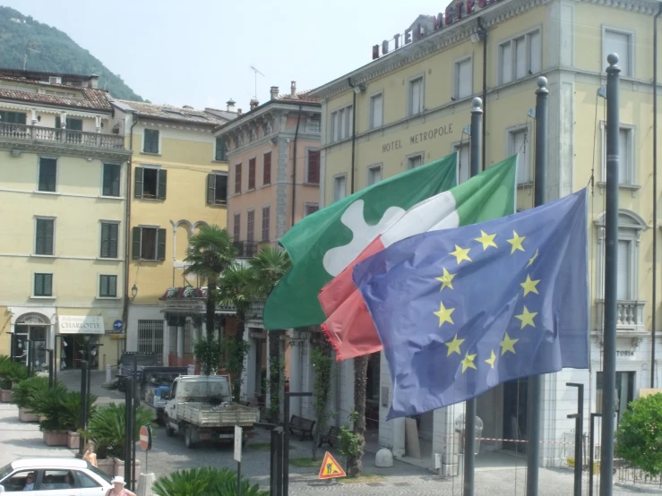 two flags flying beside each other next to a building