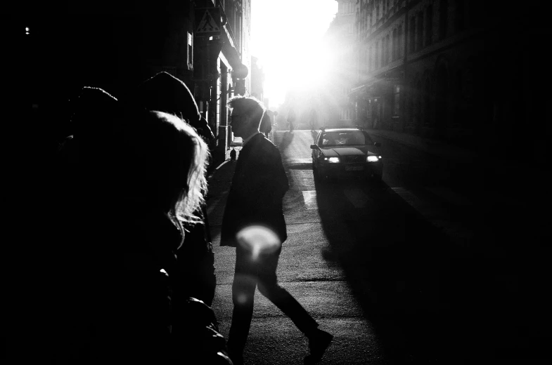 people are walking down a dark alley, with one person looking up at the sun coming through a window