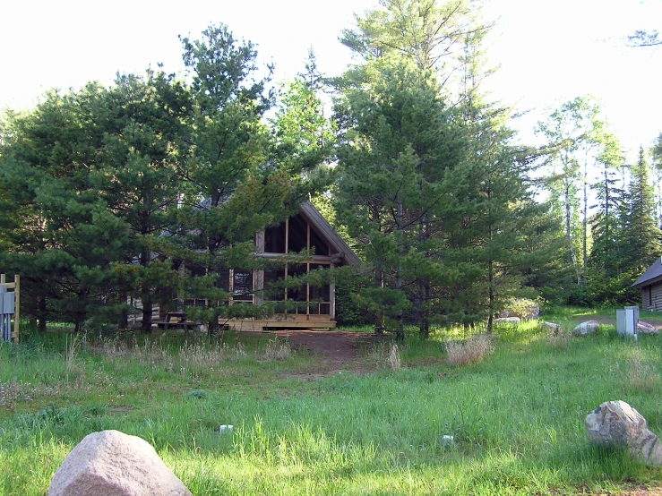 an old cabin set out in the woods with many trees around