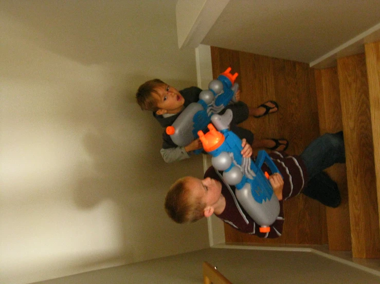 two children are holding nerf guns down stairs