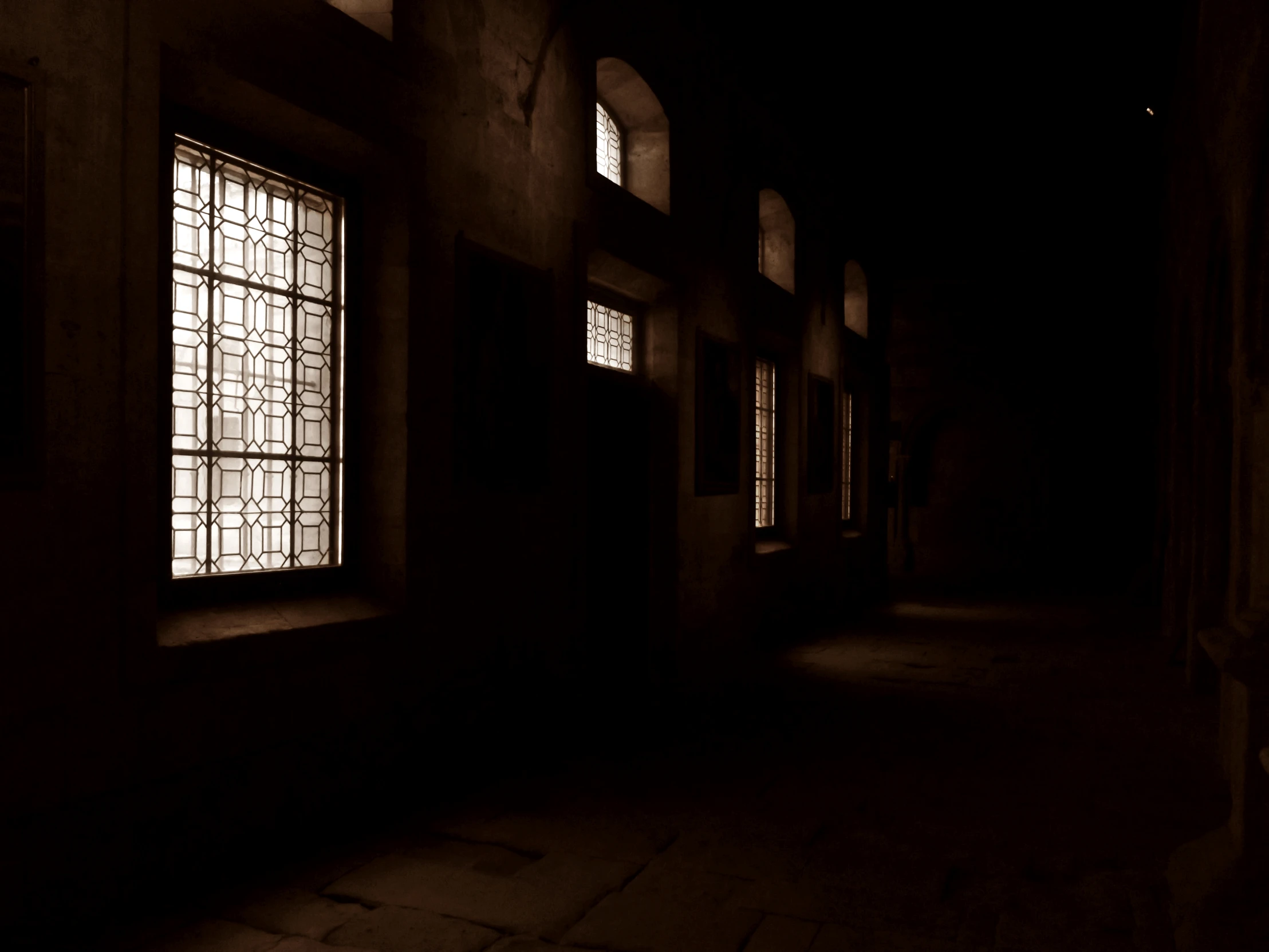 a dark hallway with windows that have been illuminated by light from the sun through them