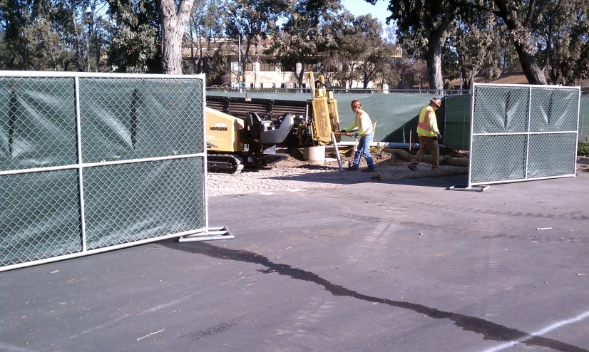 three people standing in front of fences and cars