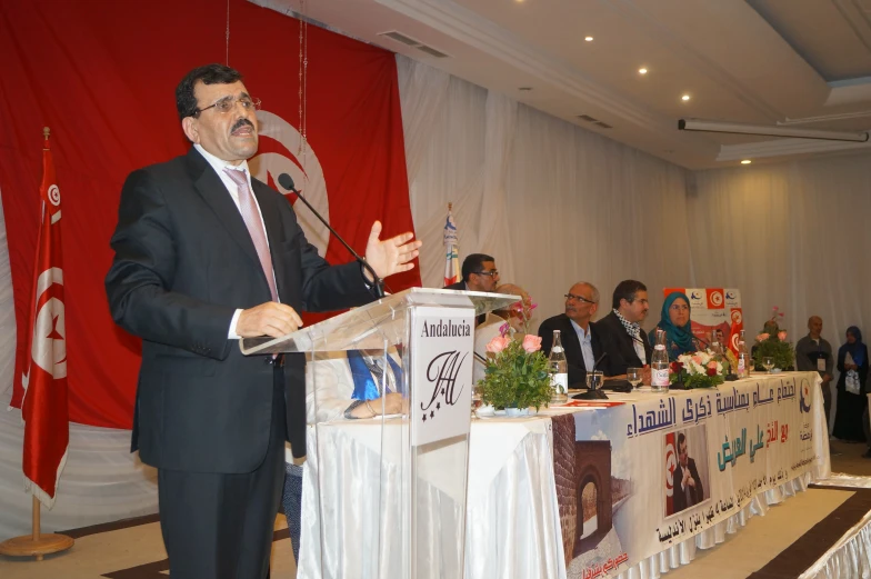 a man wearing a suit speaking to other people