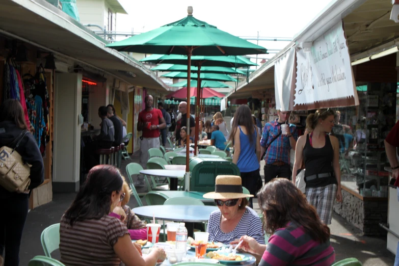 people are gathered around outside tables with umbrellas