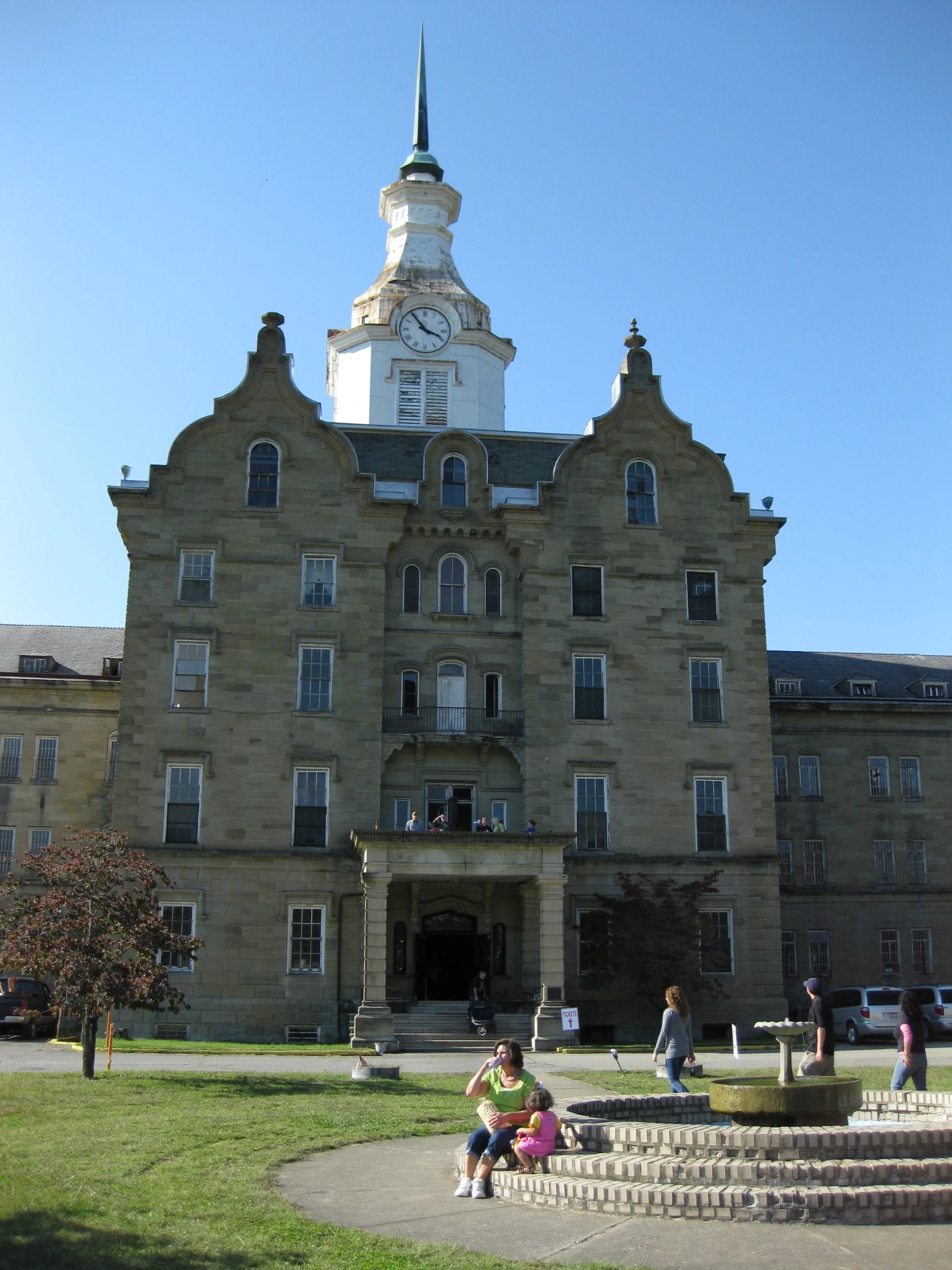 people standing in front of an old building with steps and clock tower