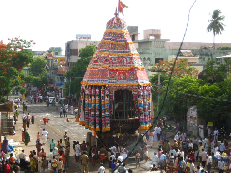 many people are walking around a colorfully decorated shrine