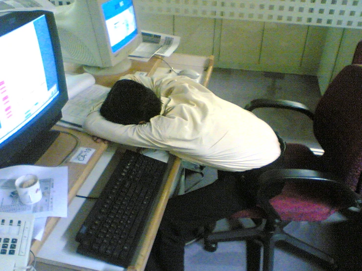 a man sleeping on his back in front of a desk