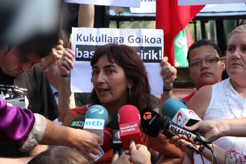 woman with microphones surrounded by people with signs