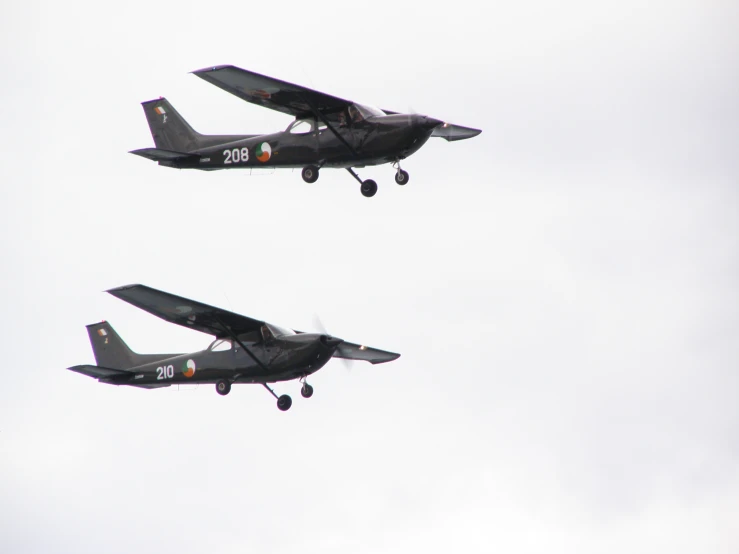 two black air planes flying against a cloudy gray sky