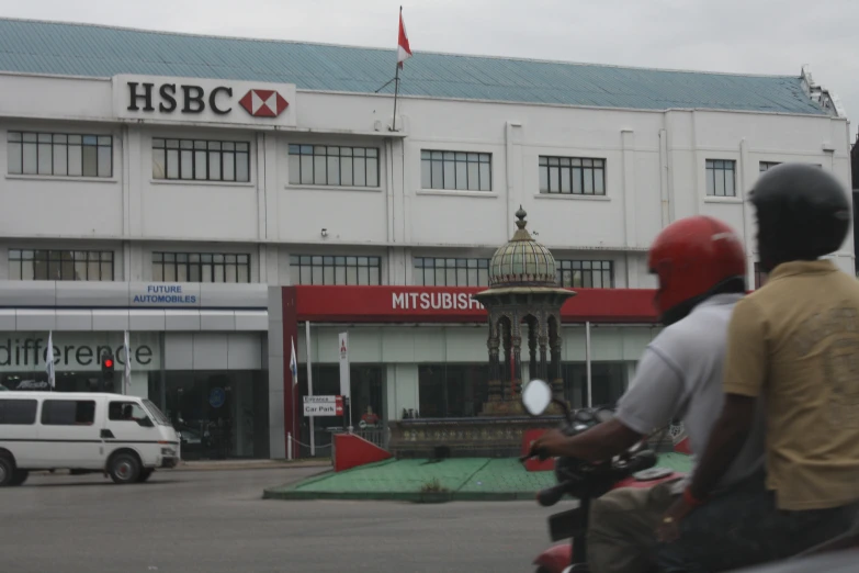 two people riding motorcycles in front of a building