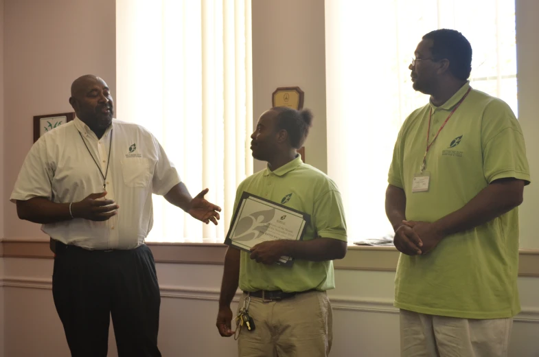 two men stand in front of a mirror and another man holds a clipboard