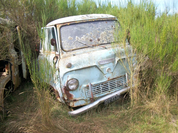 an old truck sits in the weeds