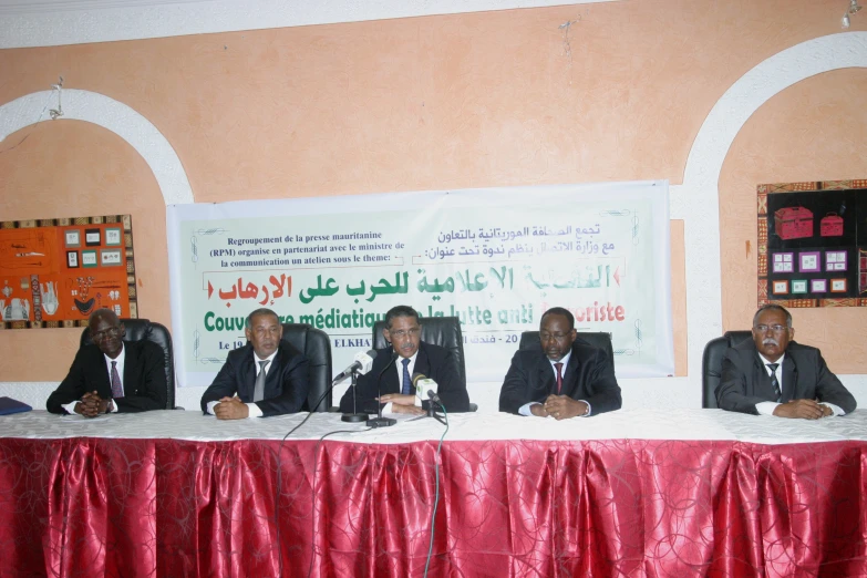 five men at a table, with two of them wearing suits and ties