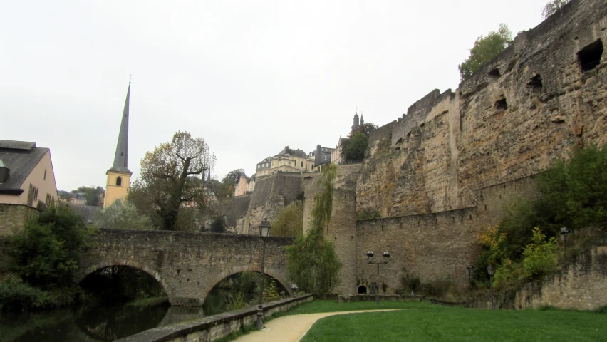 stone buildings and green grass along side an old bridge