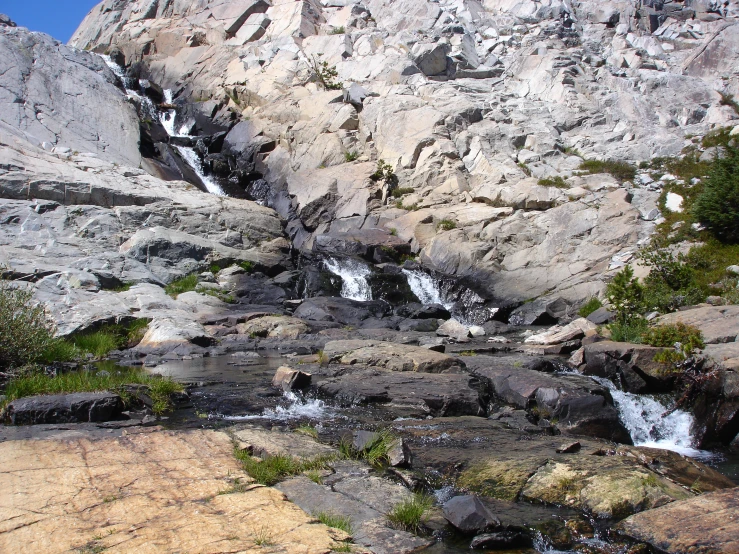 a mountain side with a waterfall and some rocks