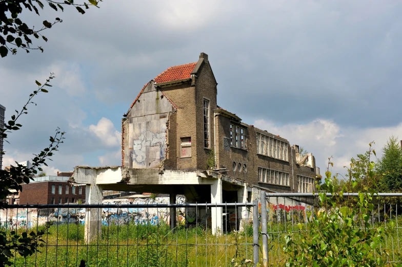 an abandoned building next to a fence on a street