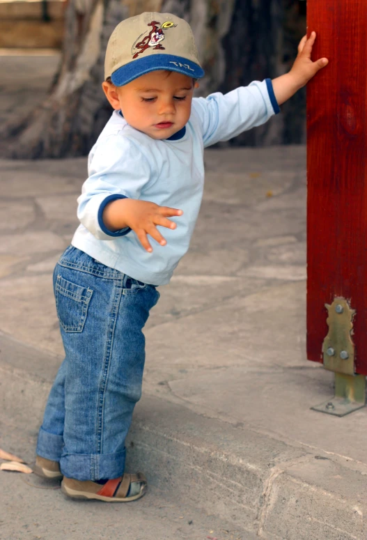 an infant standing in the street playing with a small door