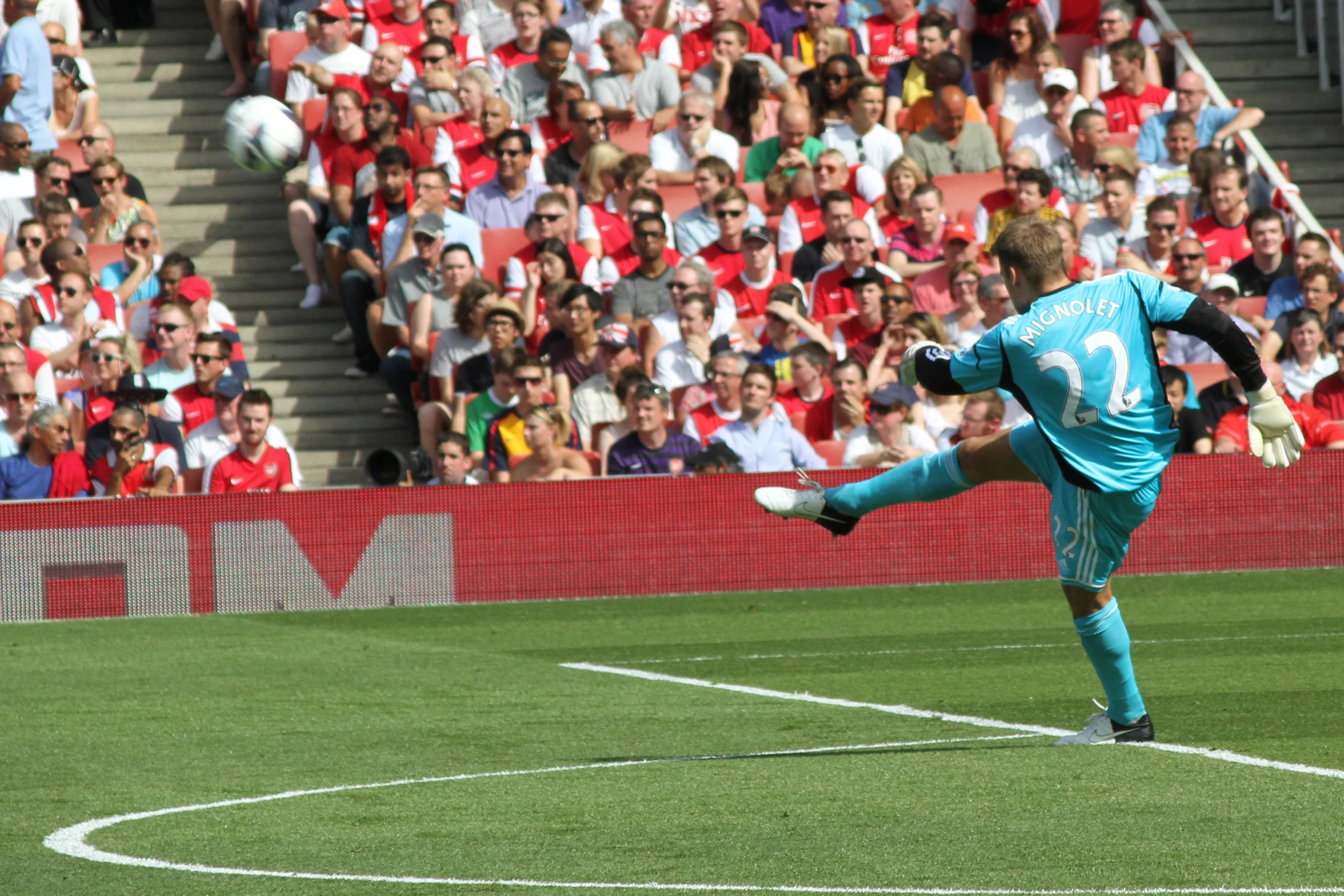 man kicking soccer ball during a professional game with spectators