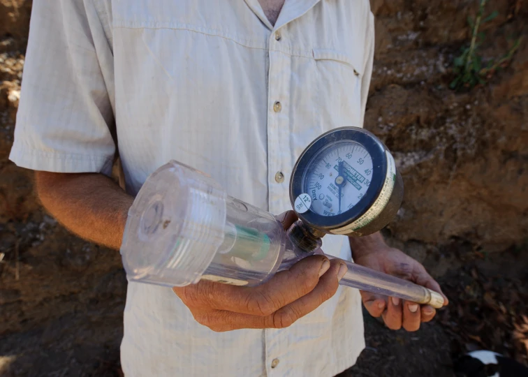 man holding an amp with a glass thermometer on it