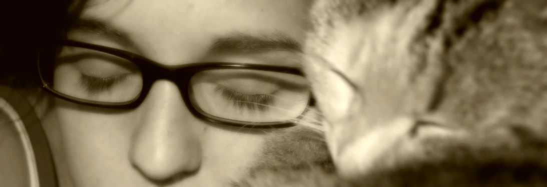 a man with eye glasses holding a cat next to his face