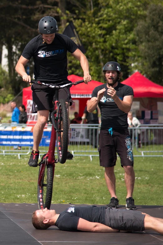 a man on a bike standing over a person on a unicycle