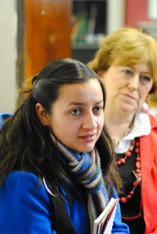 two women in scarves sitting at a desk