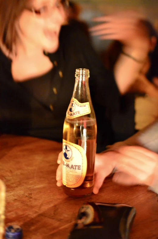 a woman standing at a table with a bottle on it