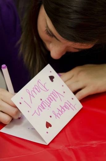 the girl is writing her congratulations card for someone