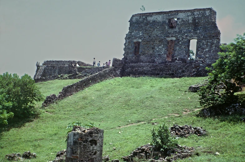 some people walking around a stone structure near trees