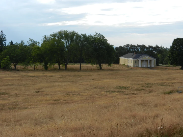 a small white building standing in the middle of some dry grass