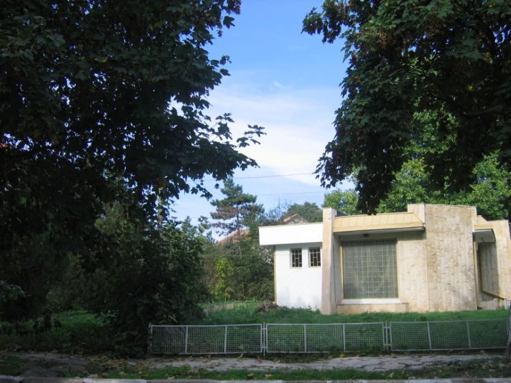 a house with a gate next to it and trees around