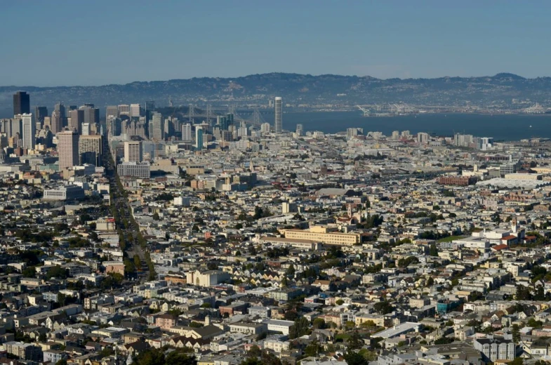 the view of a city from a hill with mountains in the background