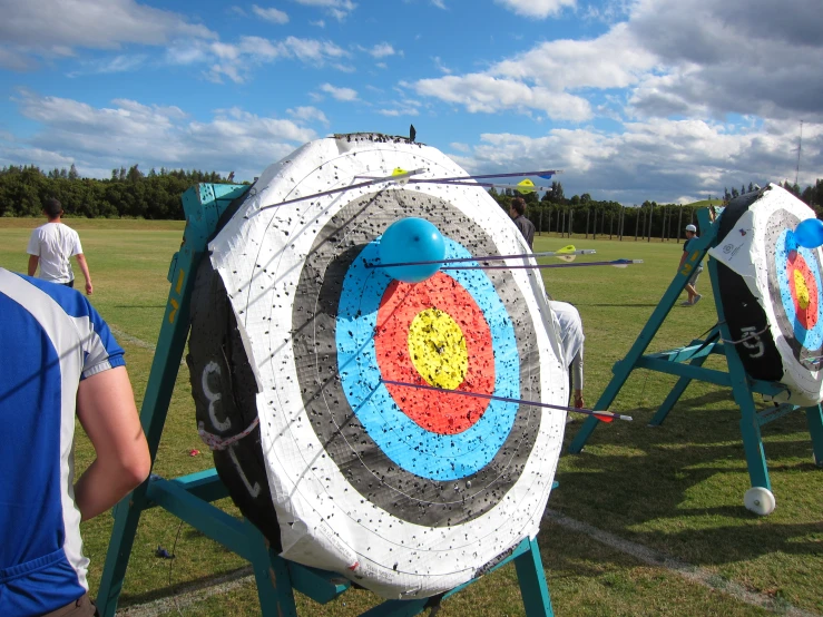 three people standing next to two large archery target