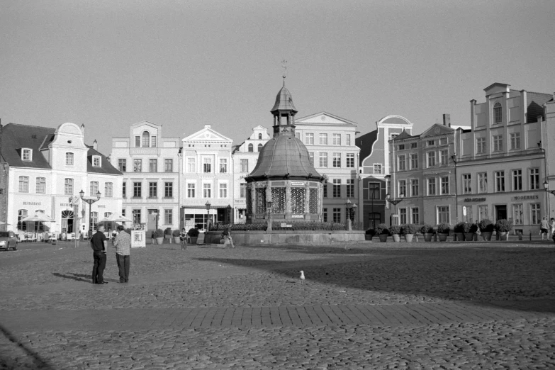 black and white pograph of several buildings and two men holding an umbrella