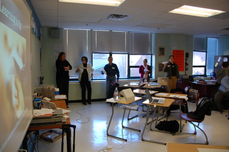 a group of people are standing in front of an image on a white board