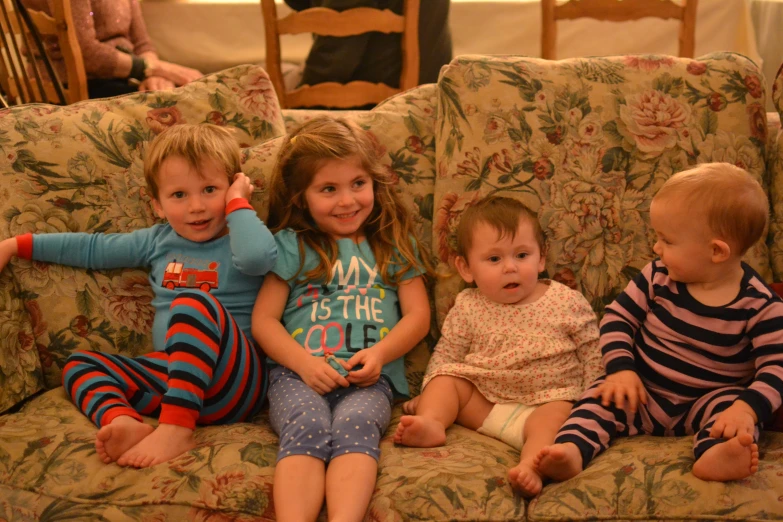 three small children sitting on a couch and one with a hairbrush